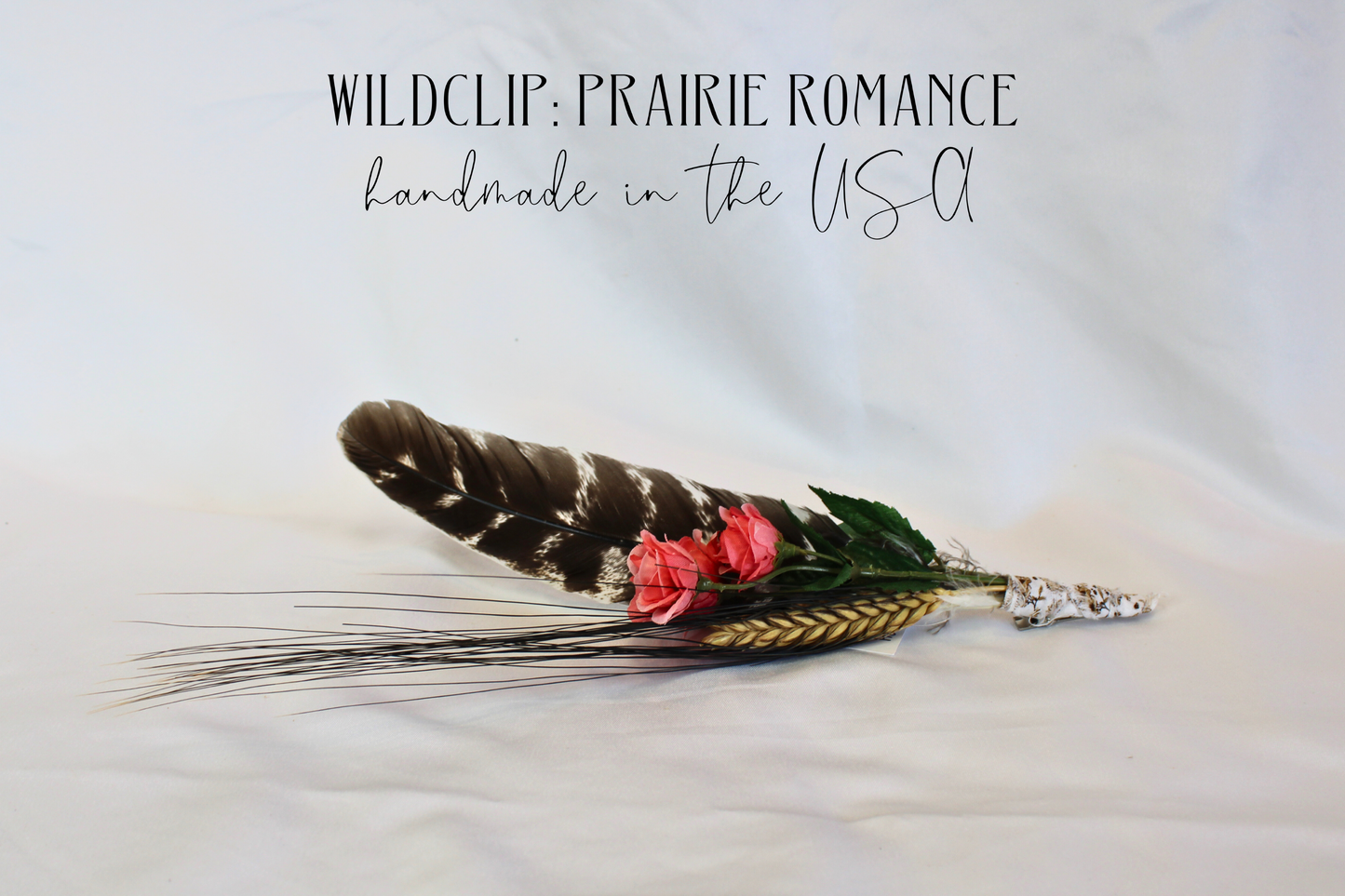 Feather hair clip with pink flower and silver clasp on a light background, labeled 'Wildclip: Prairie Romance'.