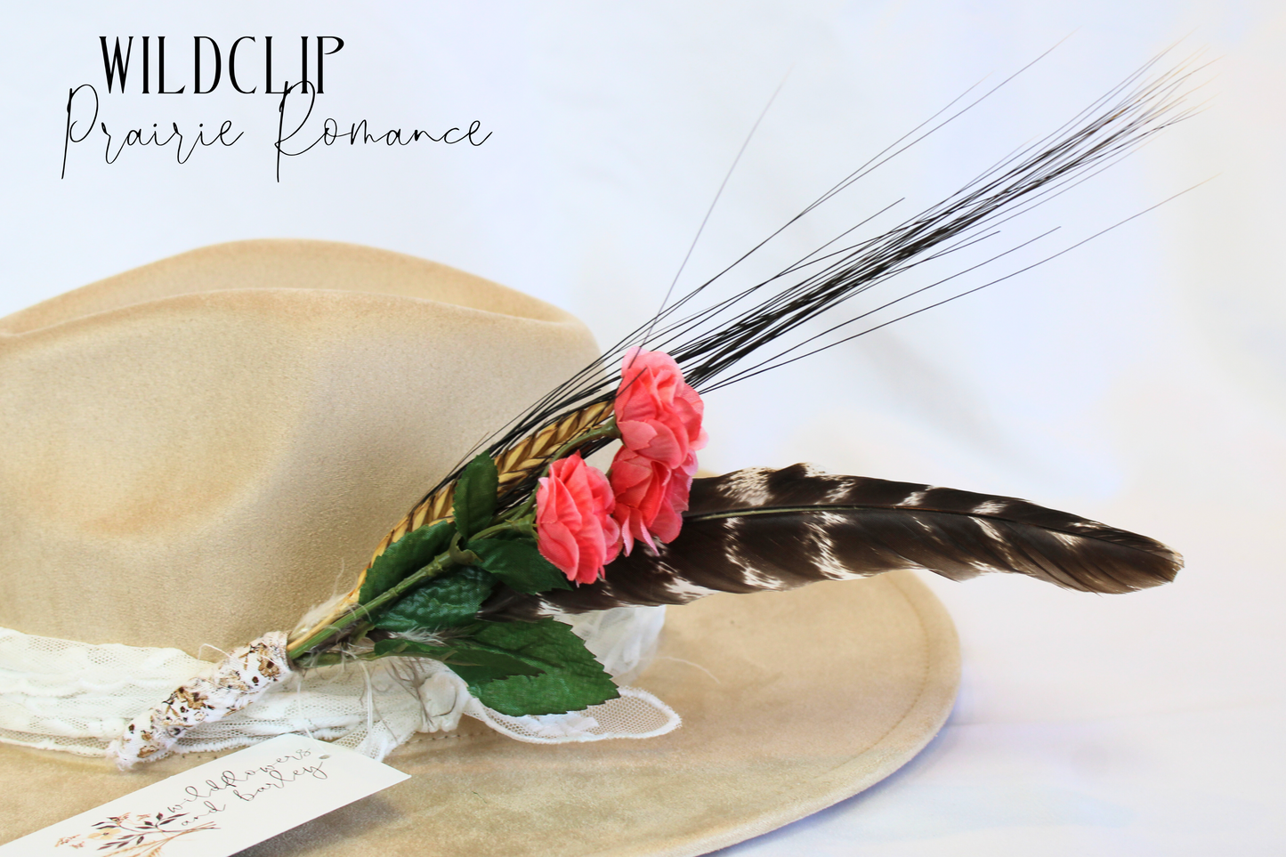 Beige hat with pink flowers and feathers on a white background, featuring 'Wildclue Prairie Romance' text.