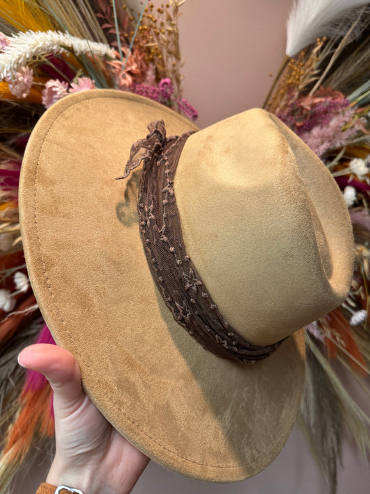 beige hat with a brown lacy hat band tied around the crown