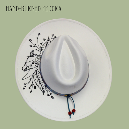 White fedora with black horse illustration and red beads on a light green background