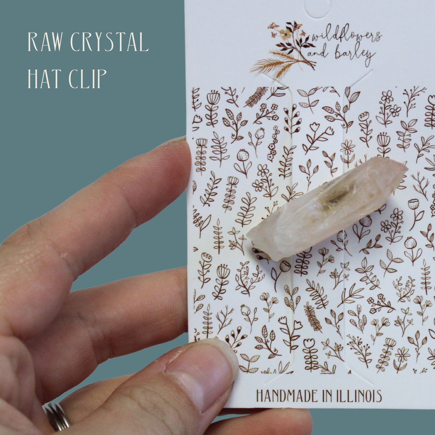 Raw crystal hat clip on a floral-patterned card held by a hand
